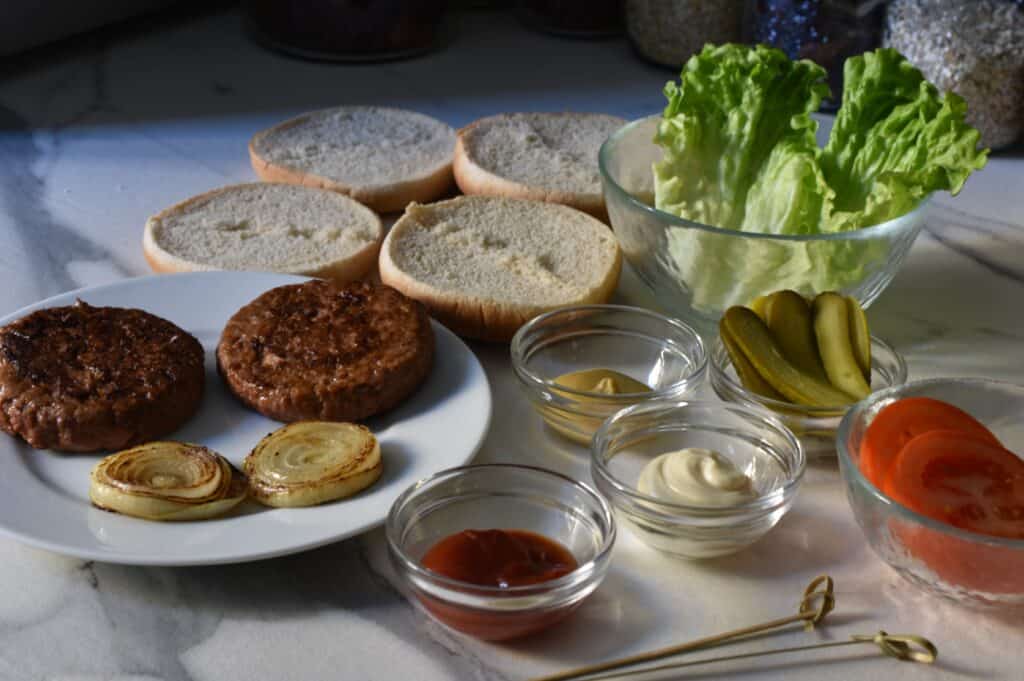 Vegan burger buns with mustard, vegan fast-food burgers, onion, tomato, gherkin, lettuce, mayonnaise and ketchup.