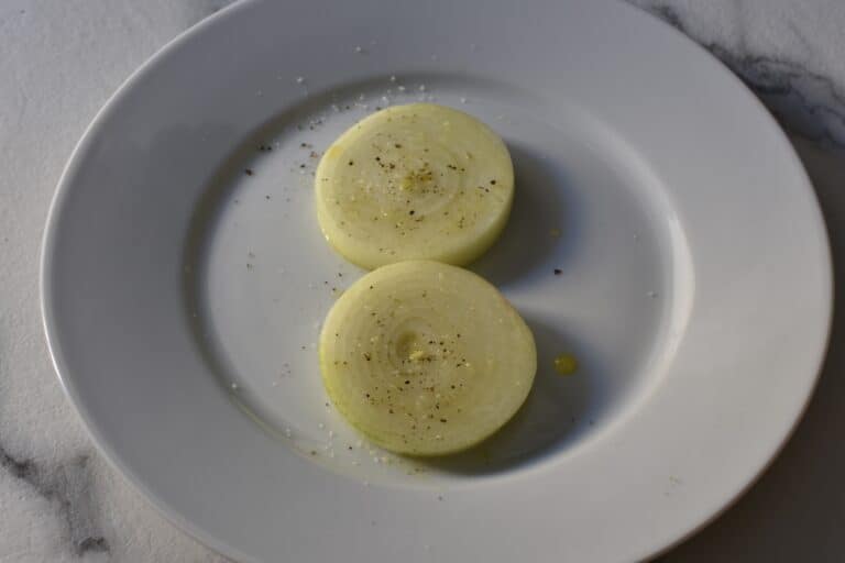 Onion slices seasoned with olive oil, salt, and black pepper.