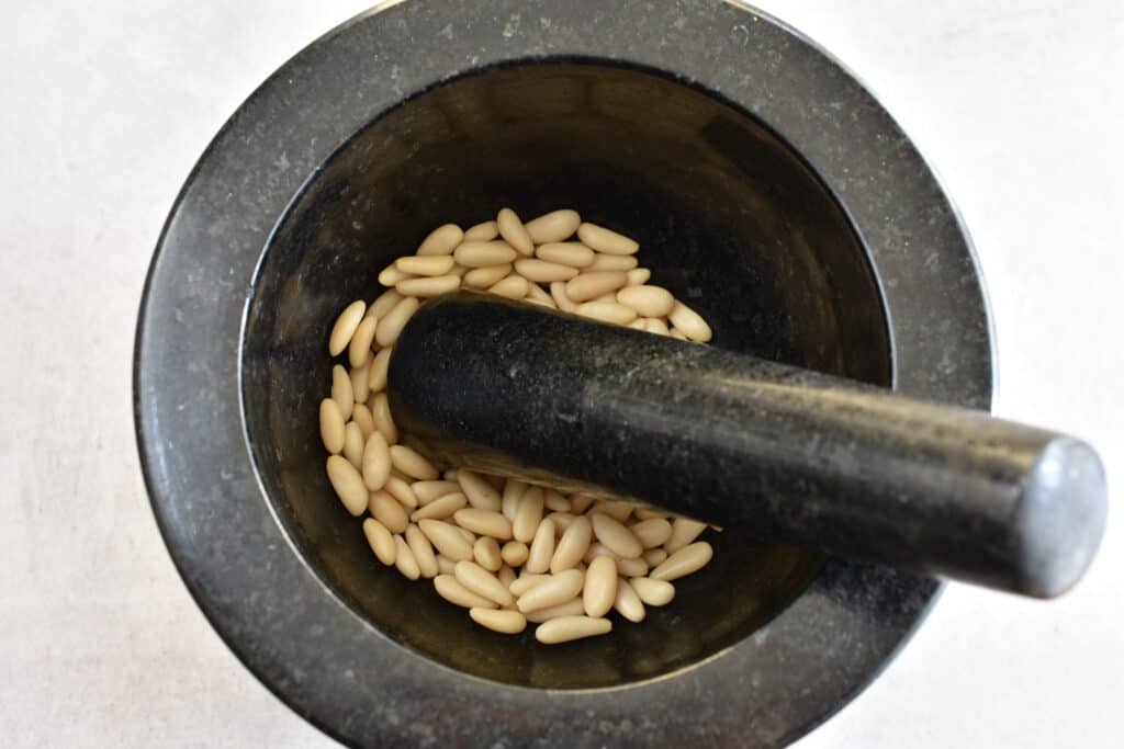 Pine nuts in a mortar with a pestle.