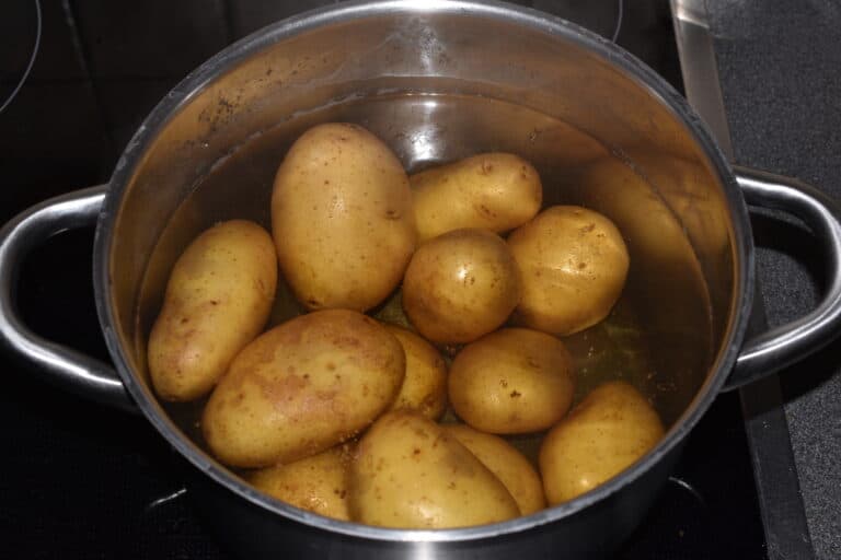 Potatoes with their skins on boiling in a pan of salted water.