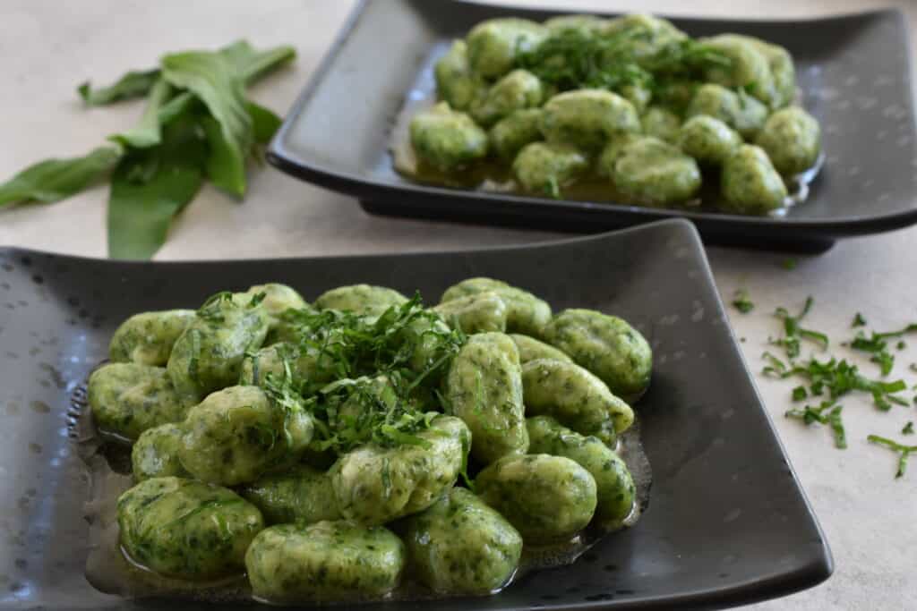 Two plates of vegan wild garlic gnocchi.