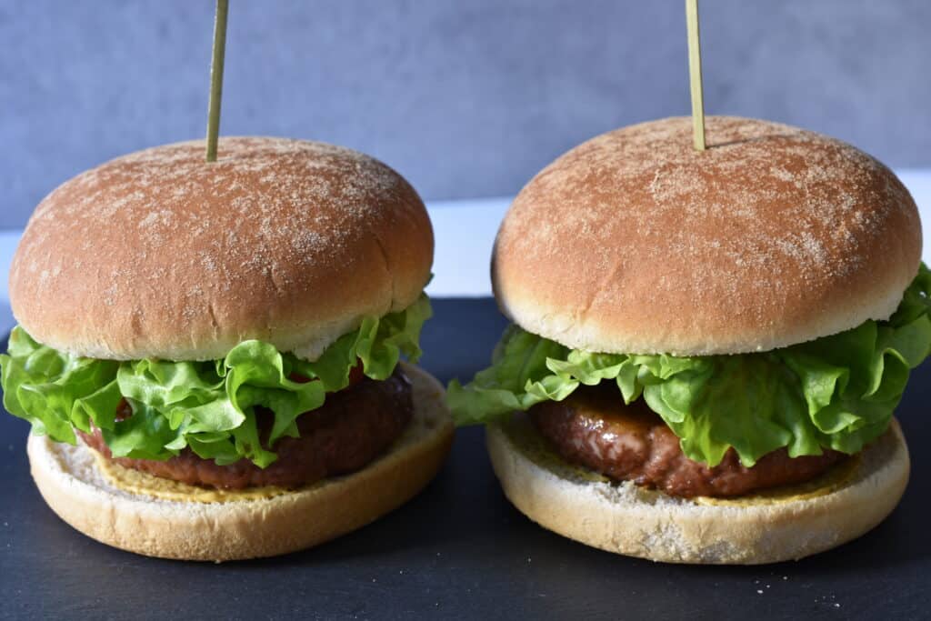 Two vegan fast food burgers on a grey slate.