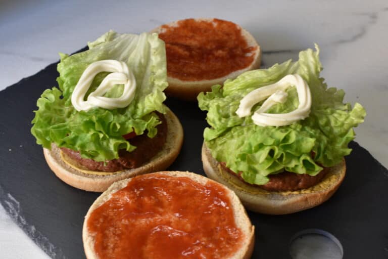 Vegan burger buns with mustard, vegan fast food burger, onions, tomato, gherkin, lettuce, mayonnaise and ketchup.