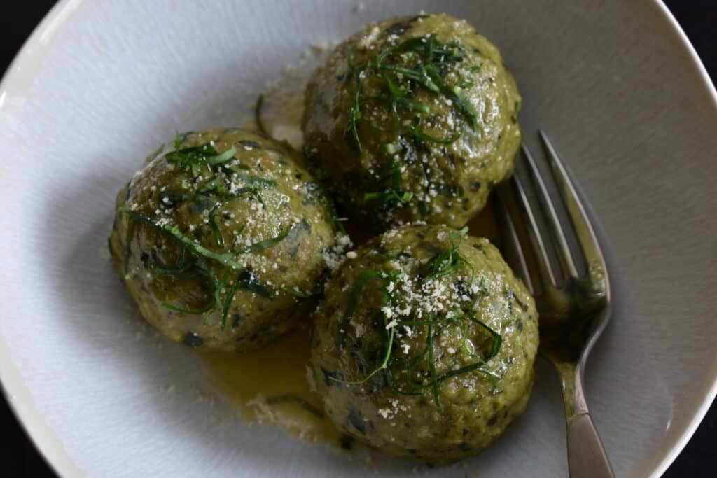 Vegan wild garlic bread dumplings with melted vegan butter and vegan parmesan cheese in a bowl with a fork.