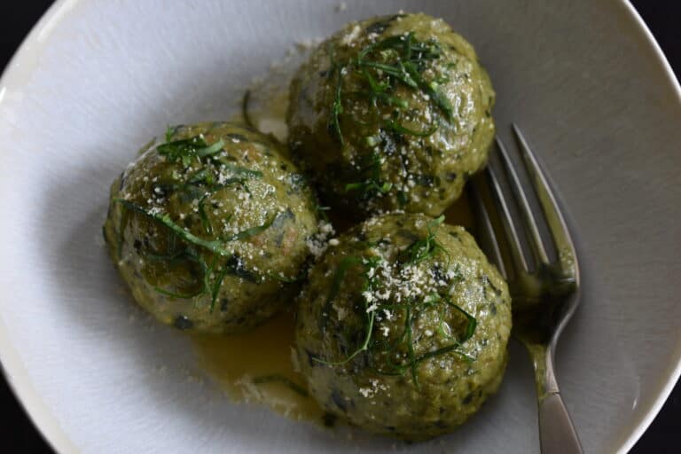 Vegan wild garlic bread dumplings with melted vegan butter and vegan parmesan cheese in a bowl with a fork.