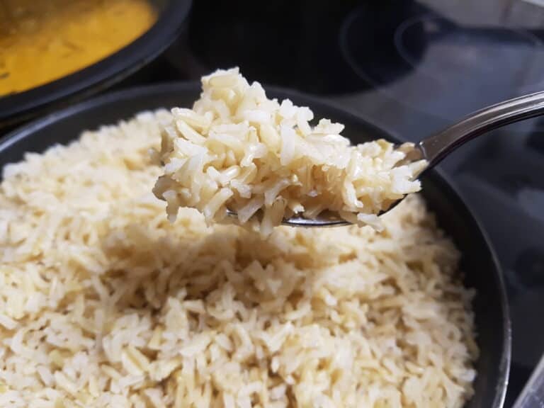 A forkful of fluffy brown basmati rice being held over a pan.