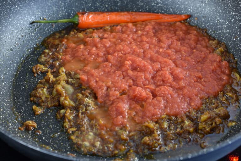 Add the tomato pulp to the sautéed onions and spices.