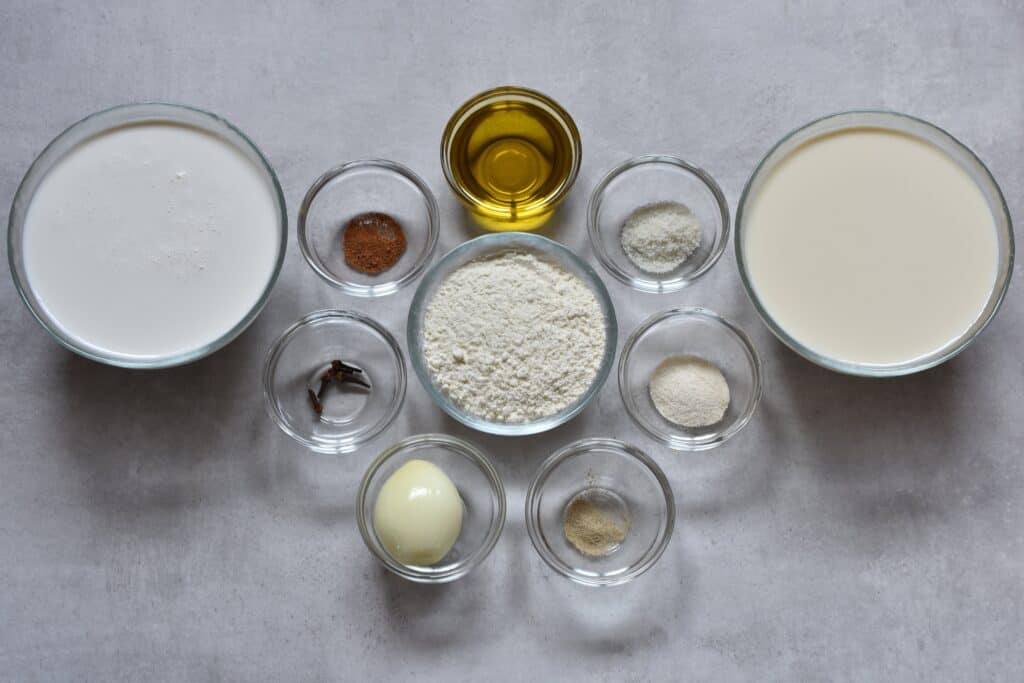 Ingredients for vegan béchamel sauce (white sauce) in glass bowls on a kitchen worktop.