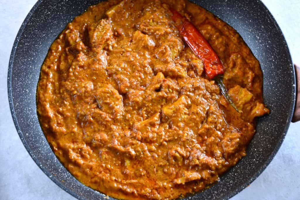 Vegan chicken tikka masala in a pan with a red chili pepper.