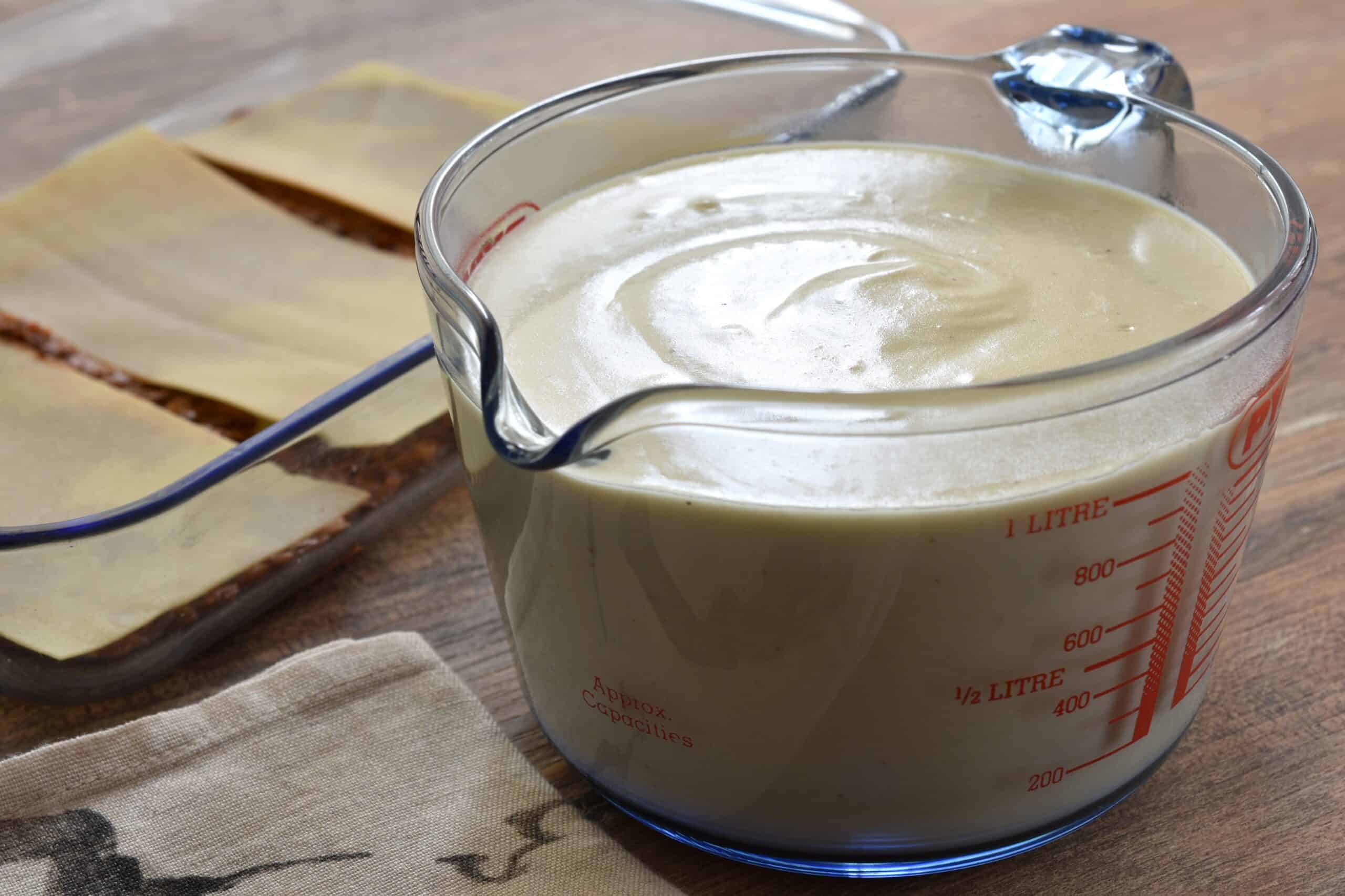 Vegan béchamel sauce in a glass measuring jug.