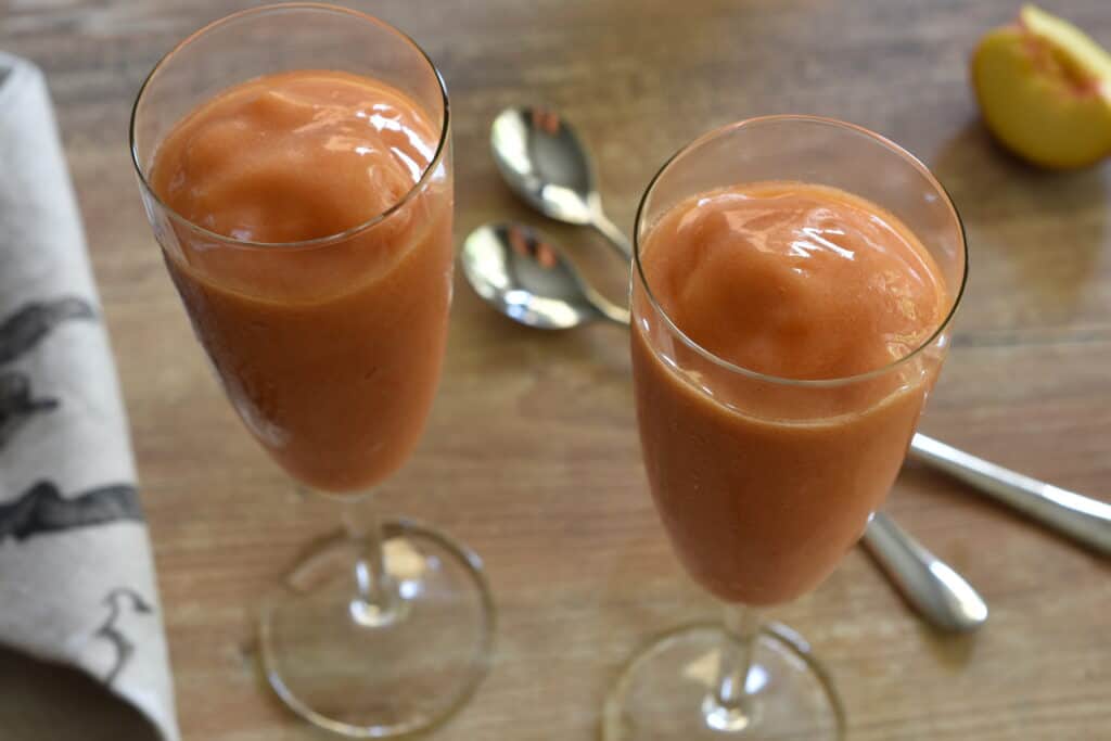 A close up image of two flute glasses of peach sorbet.