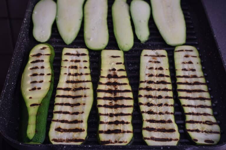 Courgettes (zucchini) being grilled on a grill pan.