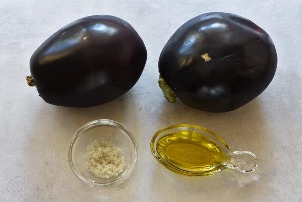 Ingredients for grilled aubergines (purple aubergines, coarse unrefined sea salt and extra virgin olive oil).