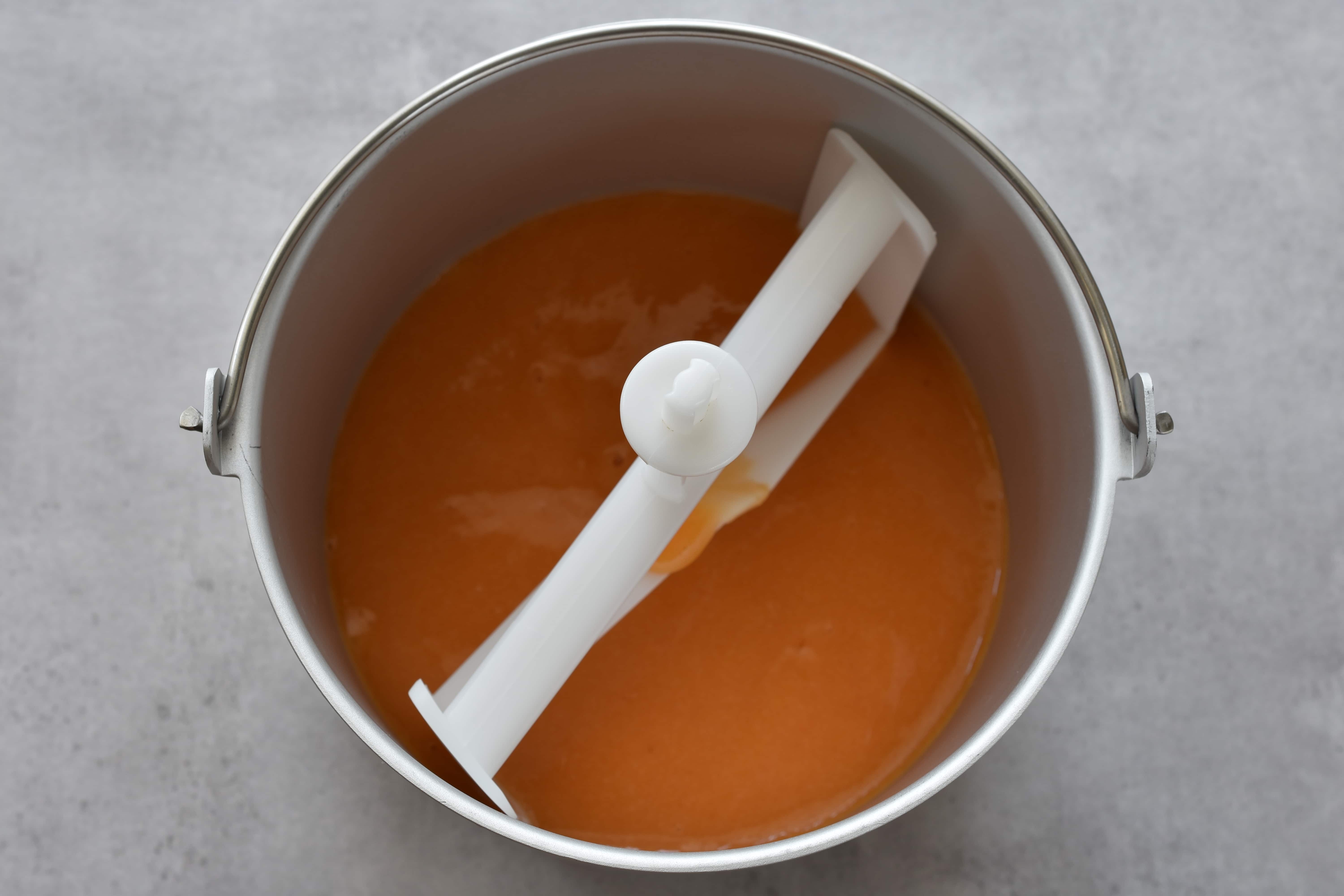 Peach sorbet mixture in the basket of an ice cream maker