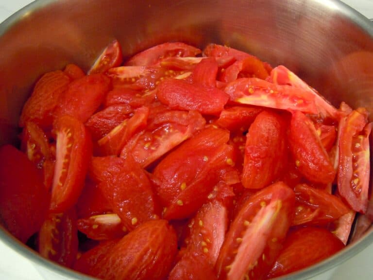 Peeled plum tomato quarters in saucepan.