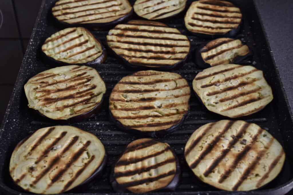 Slices of grilled aubergines on a grill pan.