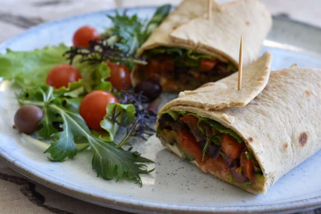 Grilled vegetable piadinas cut in a half on a plate with a garnish.