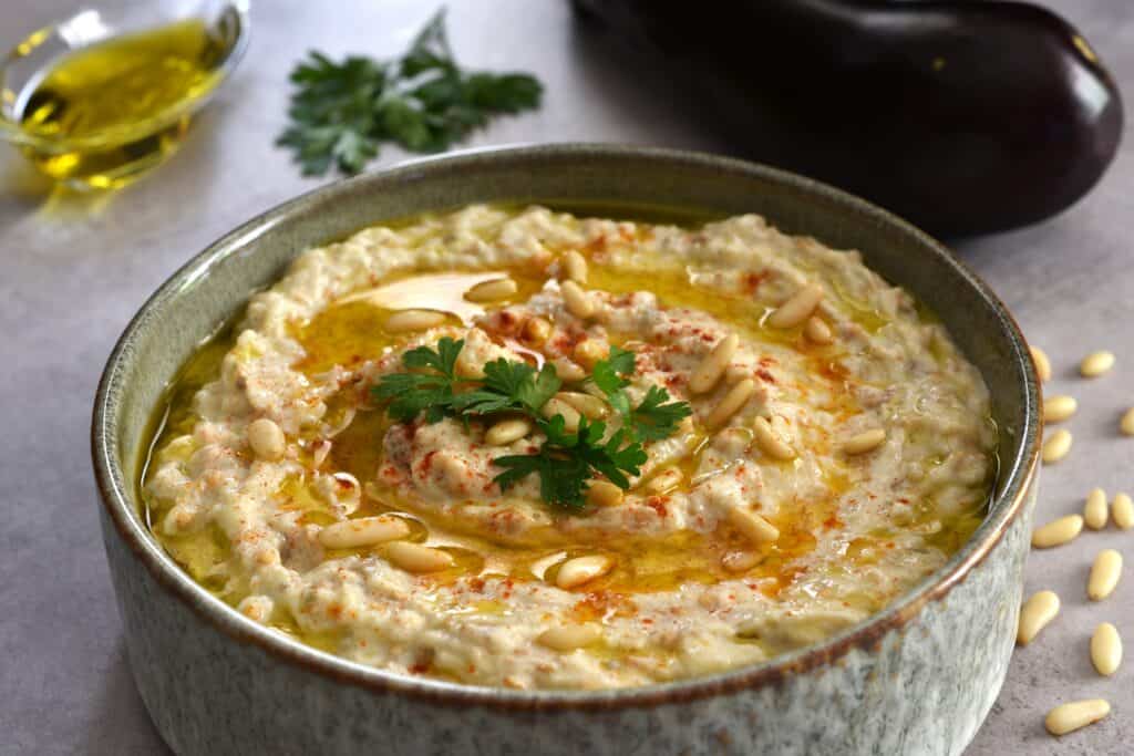 Baba ganoush (moutabal) in a dish on a table with garnish.