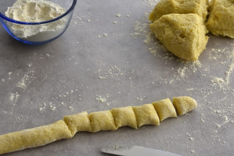 Potato gnocchi being cut into 2 cm pieces.