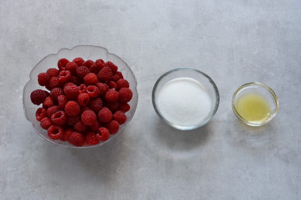 Raspberries, vegan sugar, and lemon juice in glass bowls.