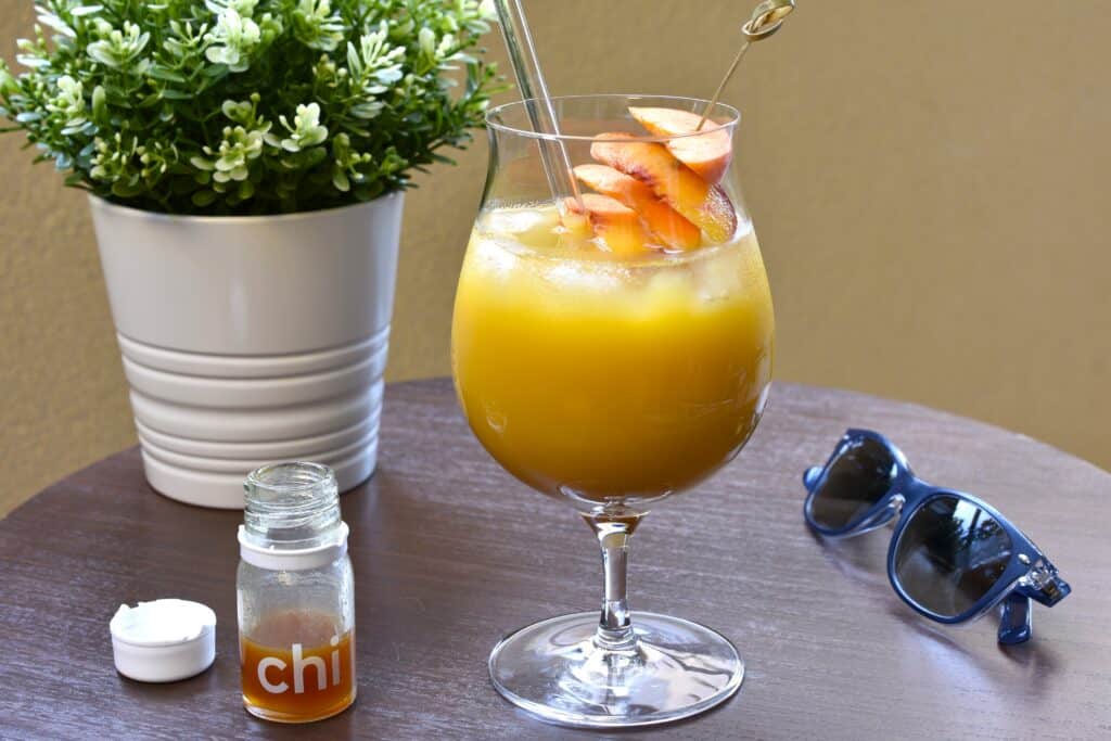 Pick-me-up fruit cocktail with Ringana chi and a garnish of fresh fruit on an outdoor table.