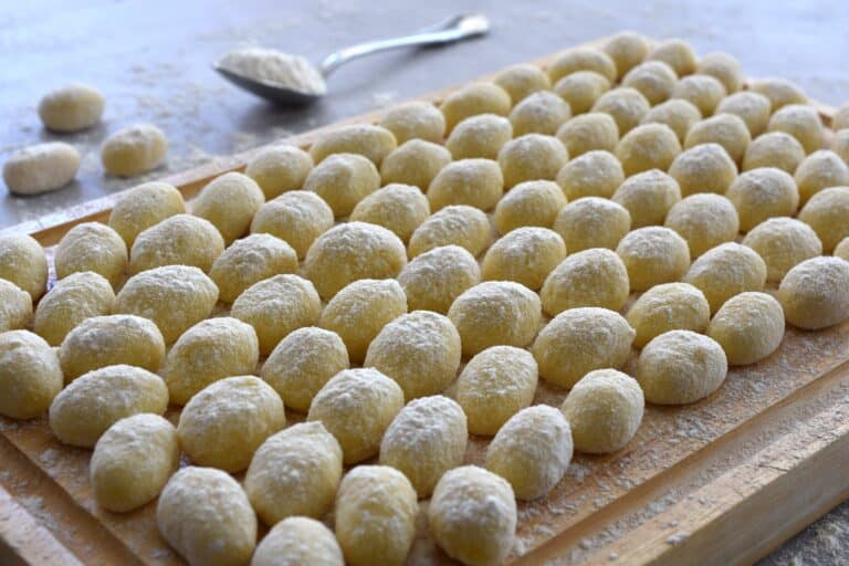 Raw potato gnocchi on a wooden board on a kitchen worktop