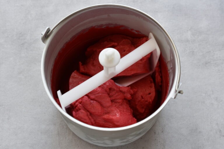 Raspberry sorbet in the basket of an ice cream maker.