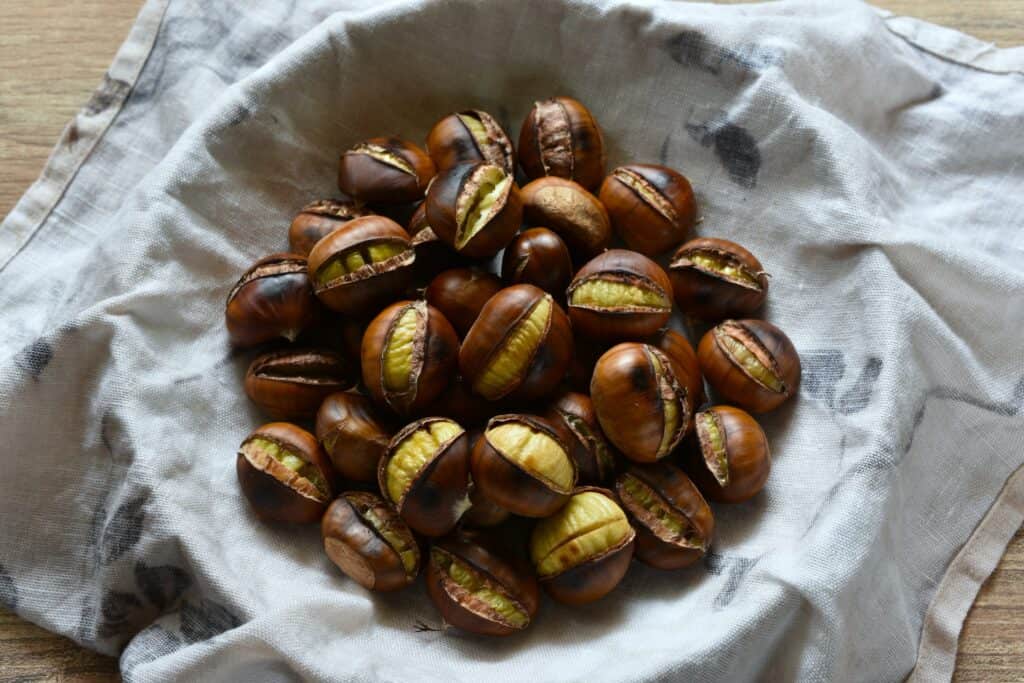 A bowl of pan-roasted chestnuts in a damp cloth.