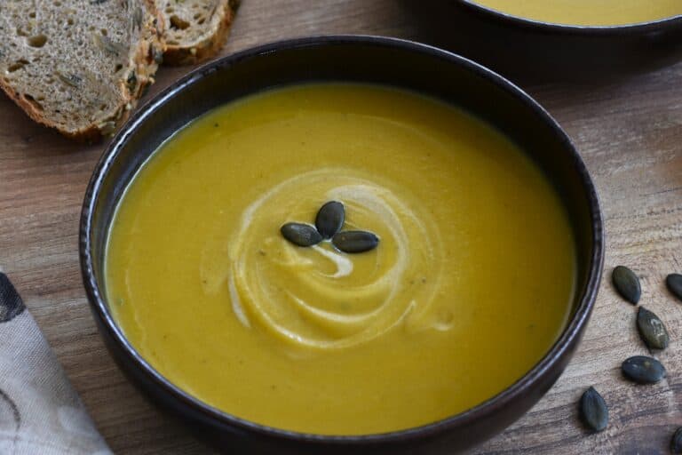 A close-up image of a bowl of pumpkin and red lentil soup.