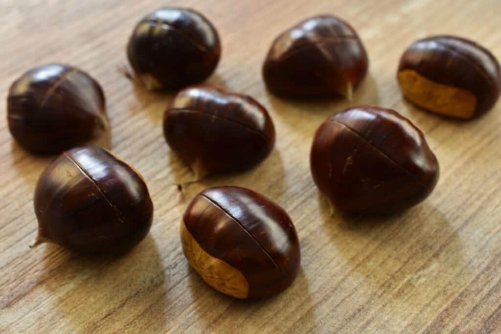 A close-up image of scored chestnuts before roasting.