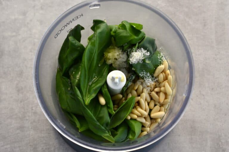 Basil leaves, pine nuts, oil , garlic, lemon juice and salt in the blender of a food processor.