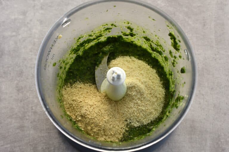 Vegan basil pesto with nutritional yeast and vegan parmesan cheese in a food processor.