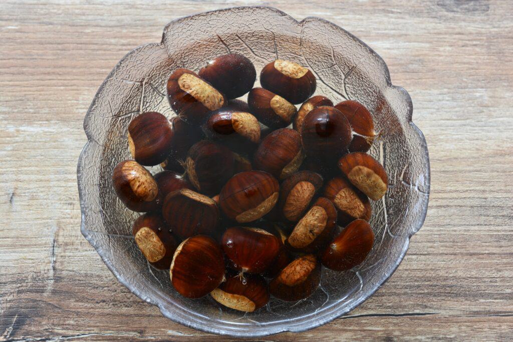 Scored chestnuts soaking in a bowl of water.