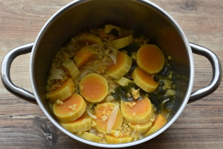 Cooked pumpkin, red split lentils, wakame, onion and celery in a sauce pan.