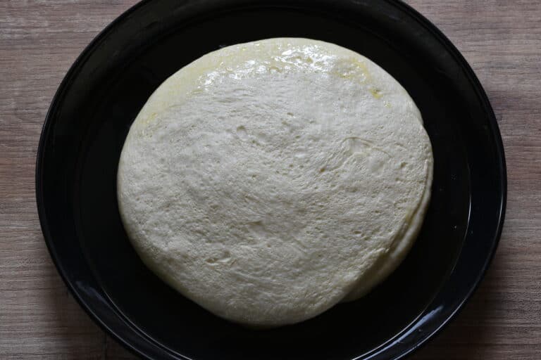 Focaccia dough on a round baking tray.