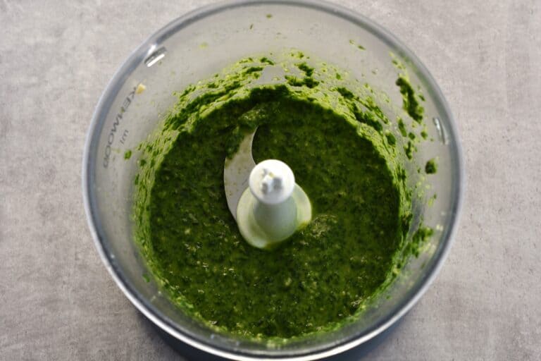 Ground basil leaves, pine nuts, oil, garlic, lemon juice, and salt, in the blender of a food processor.