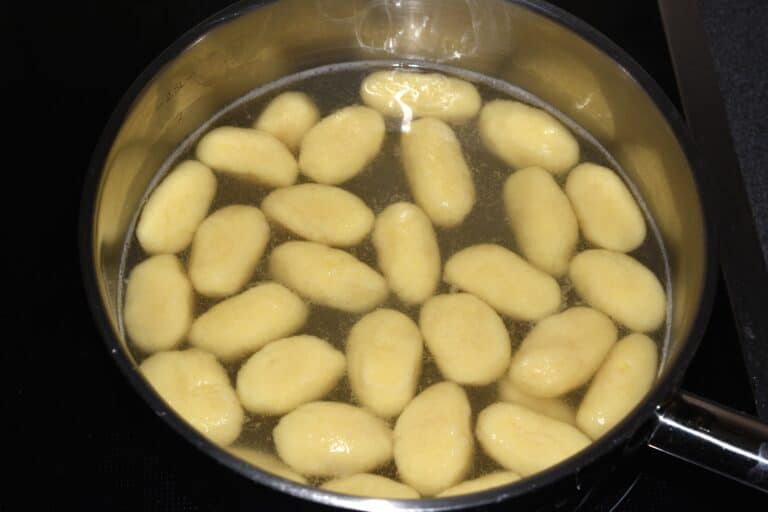 Potato gnocchi floating in a saucepan of boiling water.