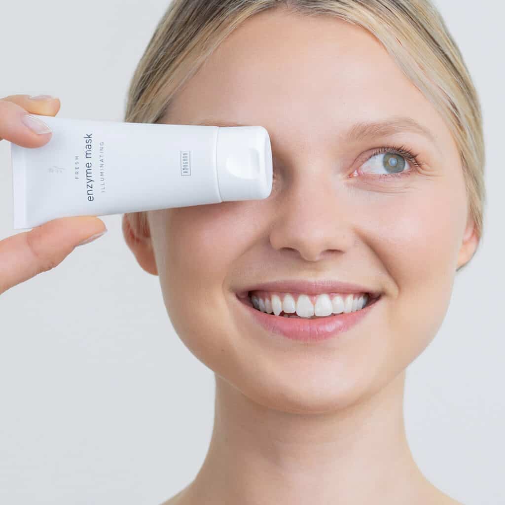 A model holding a tube of Ringana fresh vegan enzyme mask in front of her eye.