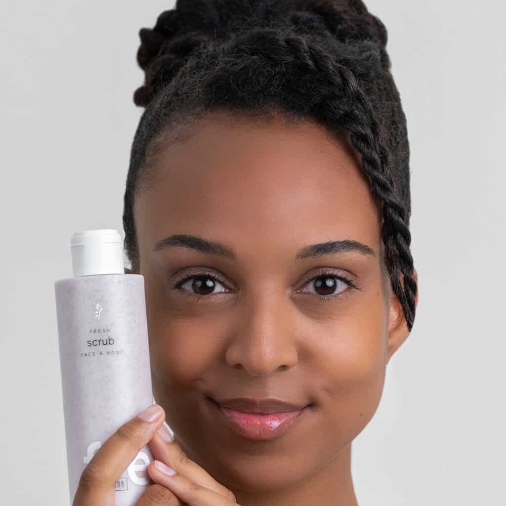 A model holding a bottle of Ringana face and body scrub.