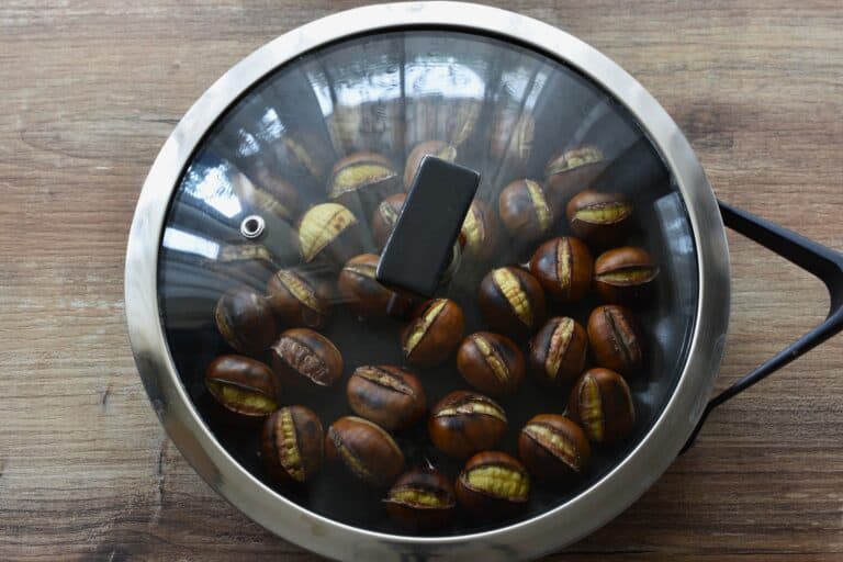 Roasted chestnuts in pan with a lid.