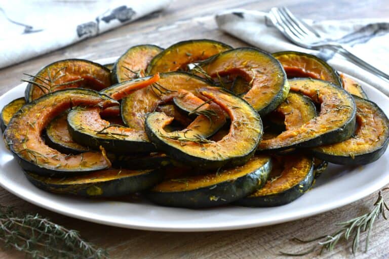 Roasted pumpkin slices with rosemary and thyme on an oval serving platter.