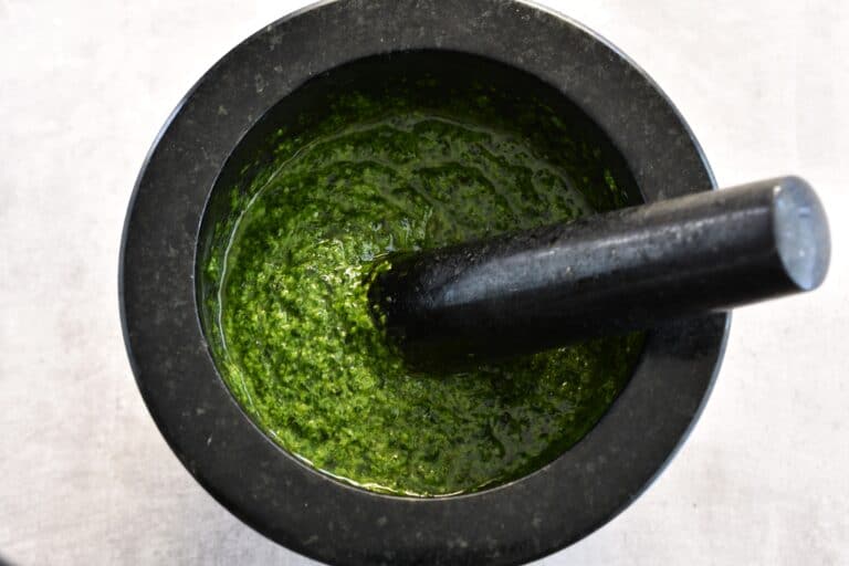 Vegan basil pesto in a mortar with a pestle.