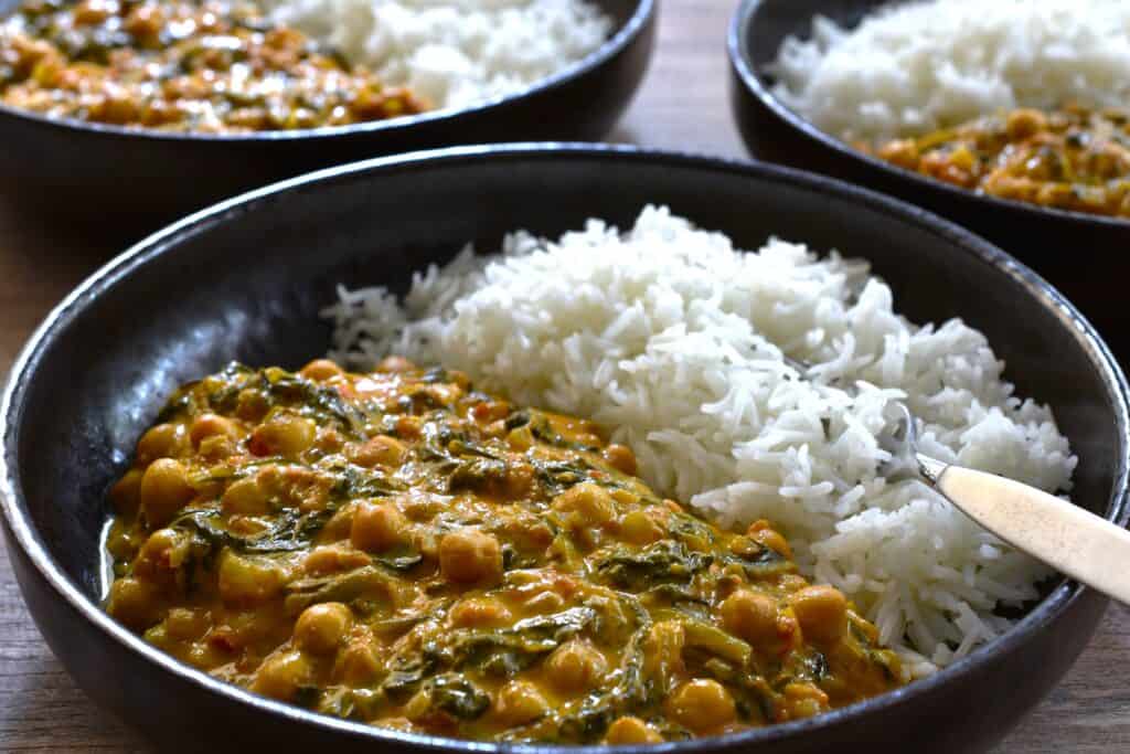 3 plates of quick vegan chickpea and spinach curry with fluffy white basmati rice.