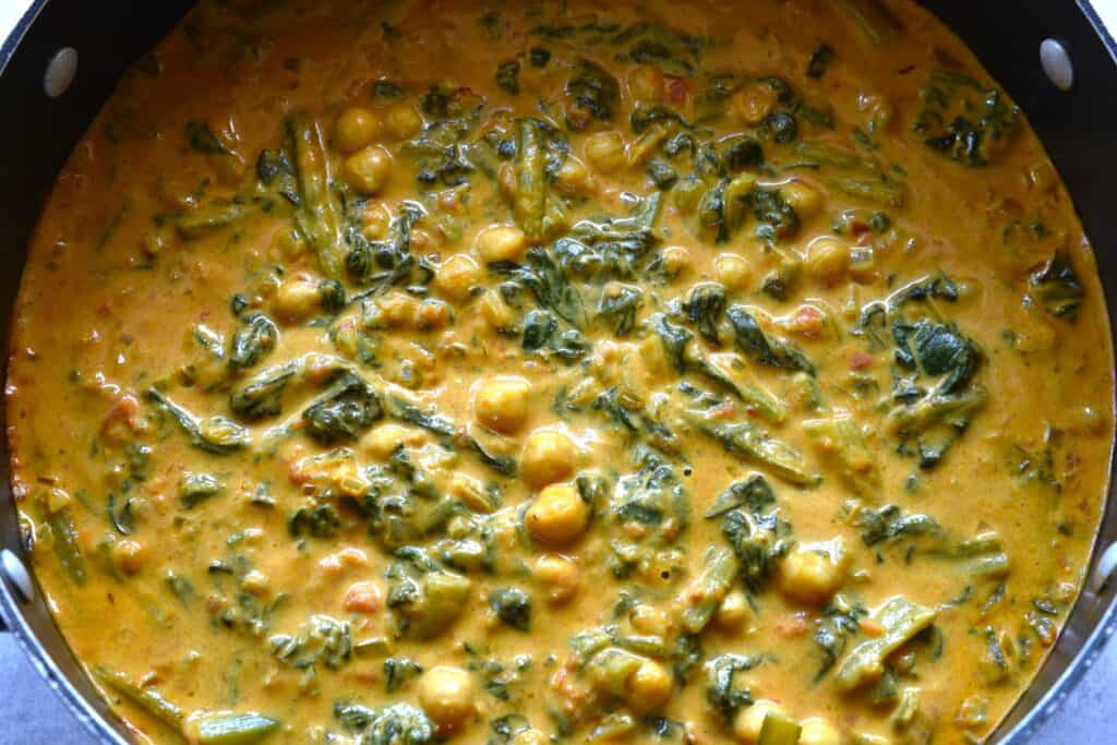 A close-up image of quick vegan chickpea and spinach curry in a big saucepan.