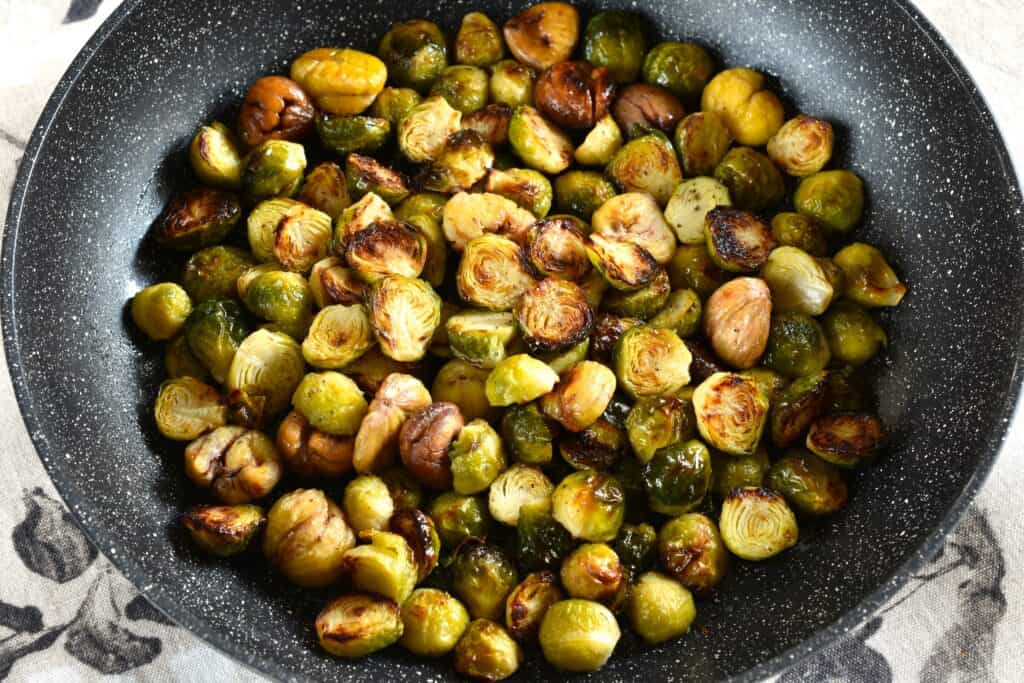 A close-up image of roasted Brussels sprouts with chestnuts in a pan.