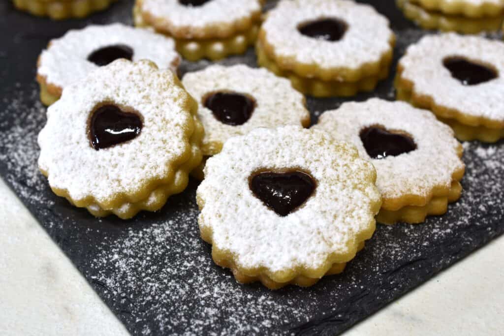 A close-up image of vegan Spitzbuben biscuits on a grey slate.