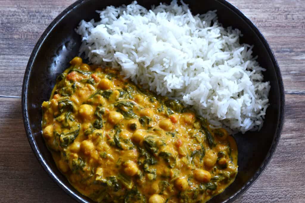 A plate of quick vegan chickpea and spinach curry with white basmati rice.