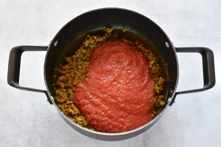 Curry paste with the addition of tomato sauce in a saucepan.