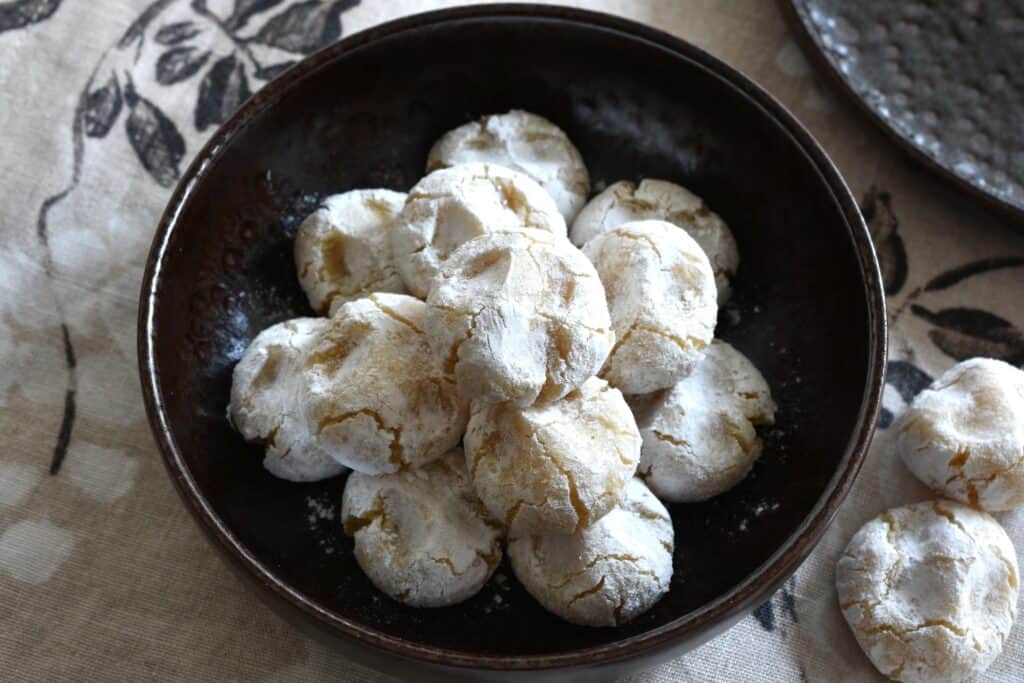 An overhead image of vegan Italian almond cookies (pizzicotti alle mandorle) in a brown bowl.