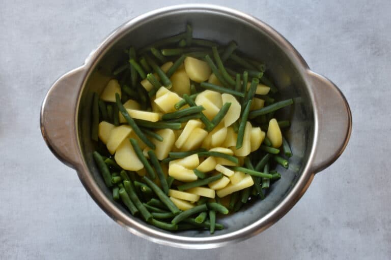 Cooked potatoes and green beans in a colander.